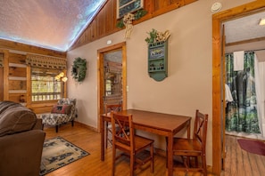 A cozy room with a wooden dining table, chairs, a patterned sofa, and a decorative wreath on the wall. - Cozy Bears Cabin (Pigeon Forge)