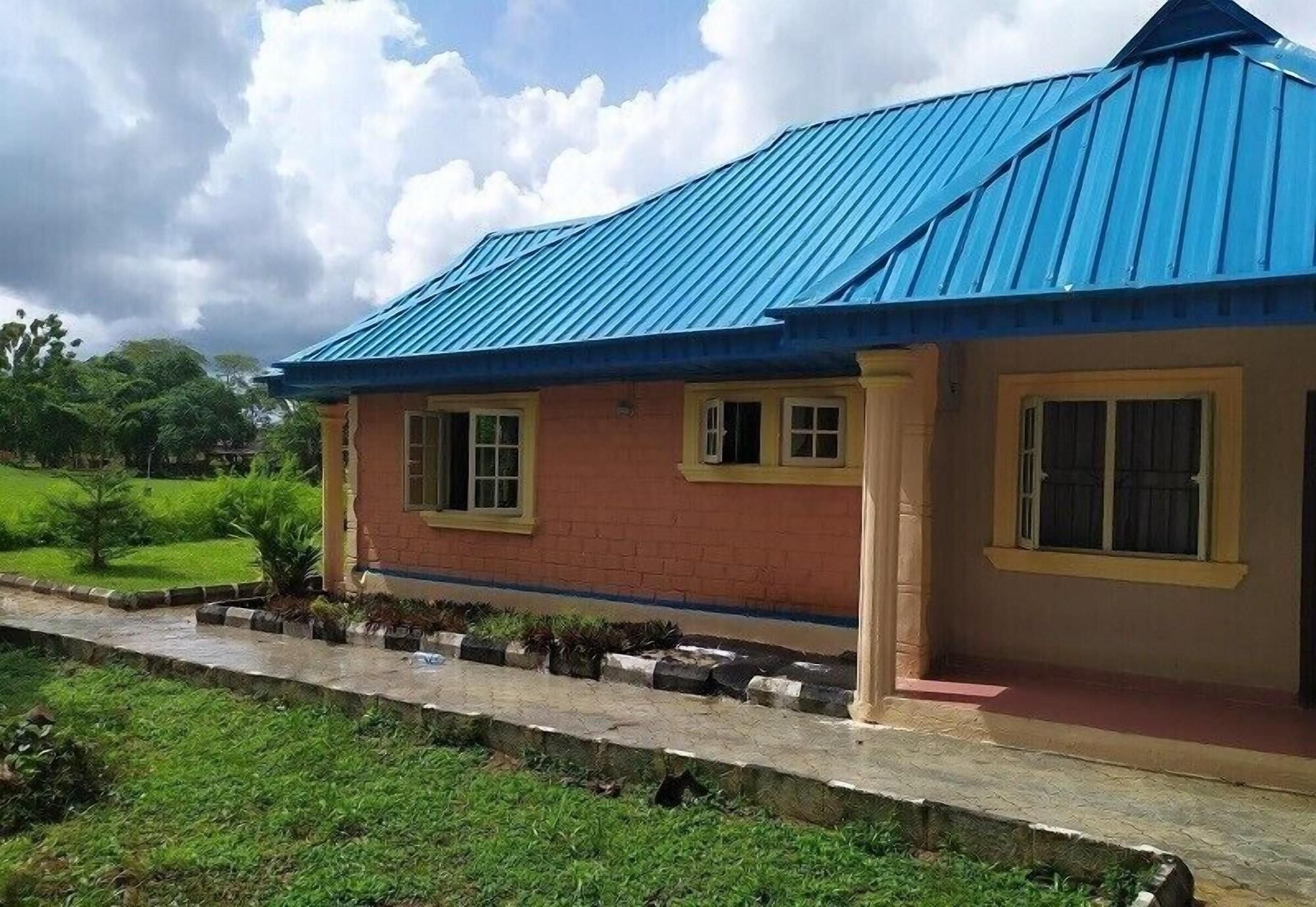 A two-story building with a blue roof, a brick facade, and a paved walkway with potted plants.