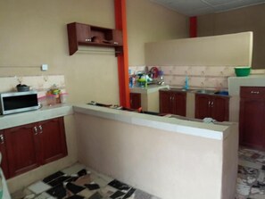 A compact kitchen with a microwave, sink, and cabinets. - Holis Resort (Lagos)