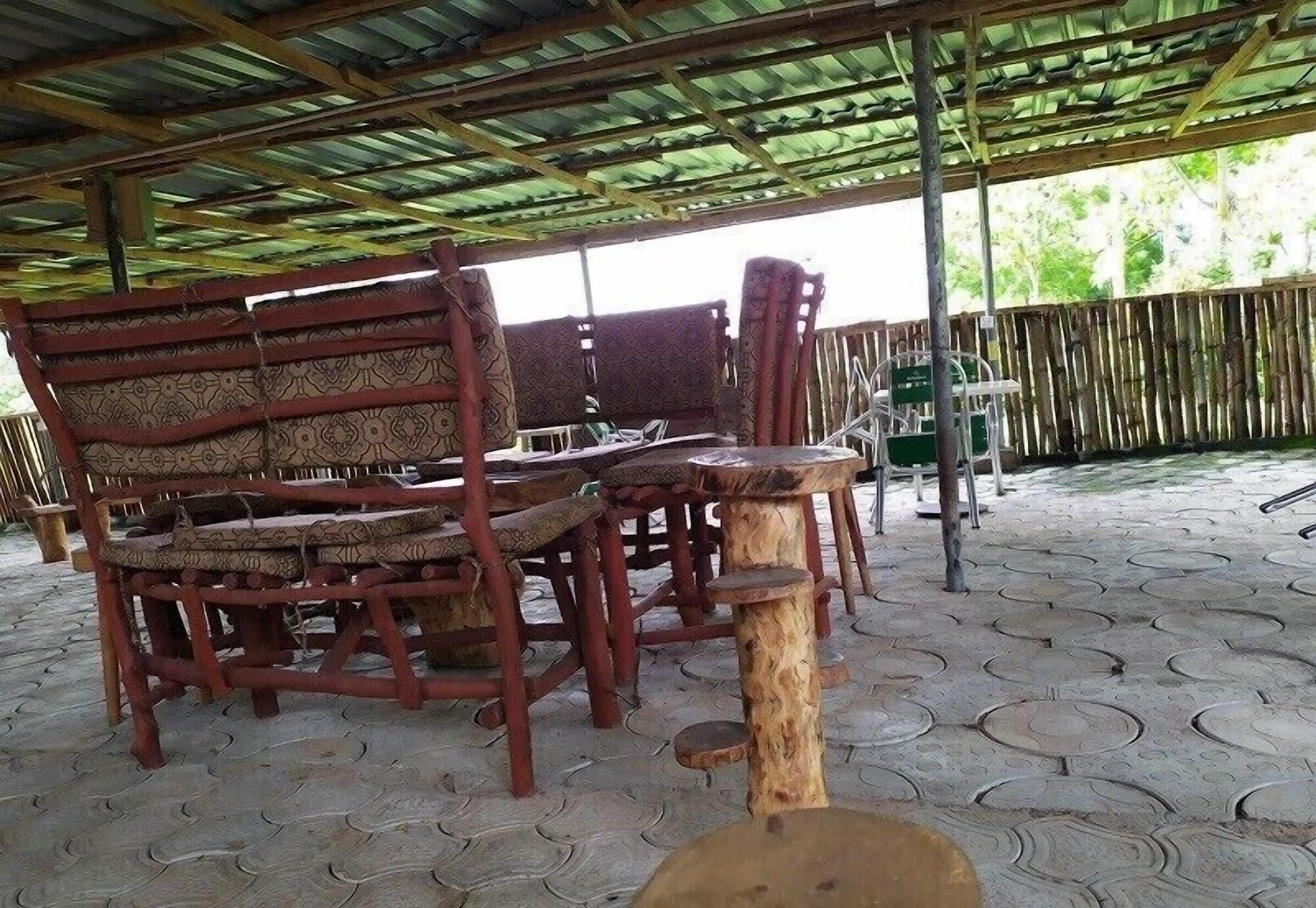 A covered outdoor seating area with wooden furniture and a tiled floor.