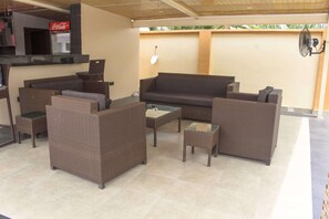 An outdoor seating area with wicker furniture, a glass-top table, and a sofa. - Villa Park Hotels (Lagos)