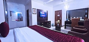 A hotel room with a bed, a TV, a desk with a chair, and a mirror. - Villa Park Hotels (Lagos)