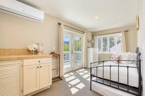 Un dormitorio con cama, cómoda, ventana y balcón.