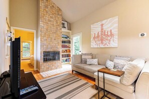 Una sala de estar con un sofá, televisor, chimenea y estantería.