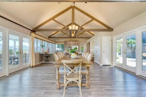 A spacious dining area with a long table, chairs, and a chandelier.