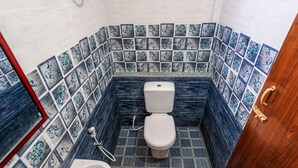 Un baño con inodoro, bidé y lavamanos. Las paredes están cubiertas de azulejos con un diseño azul y blanco.