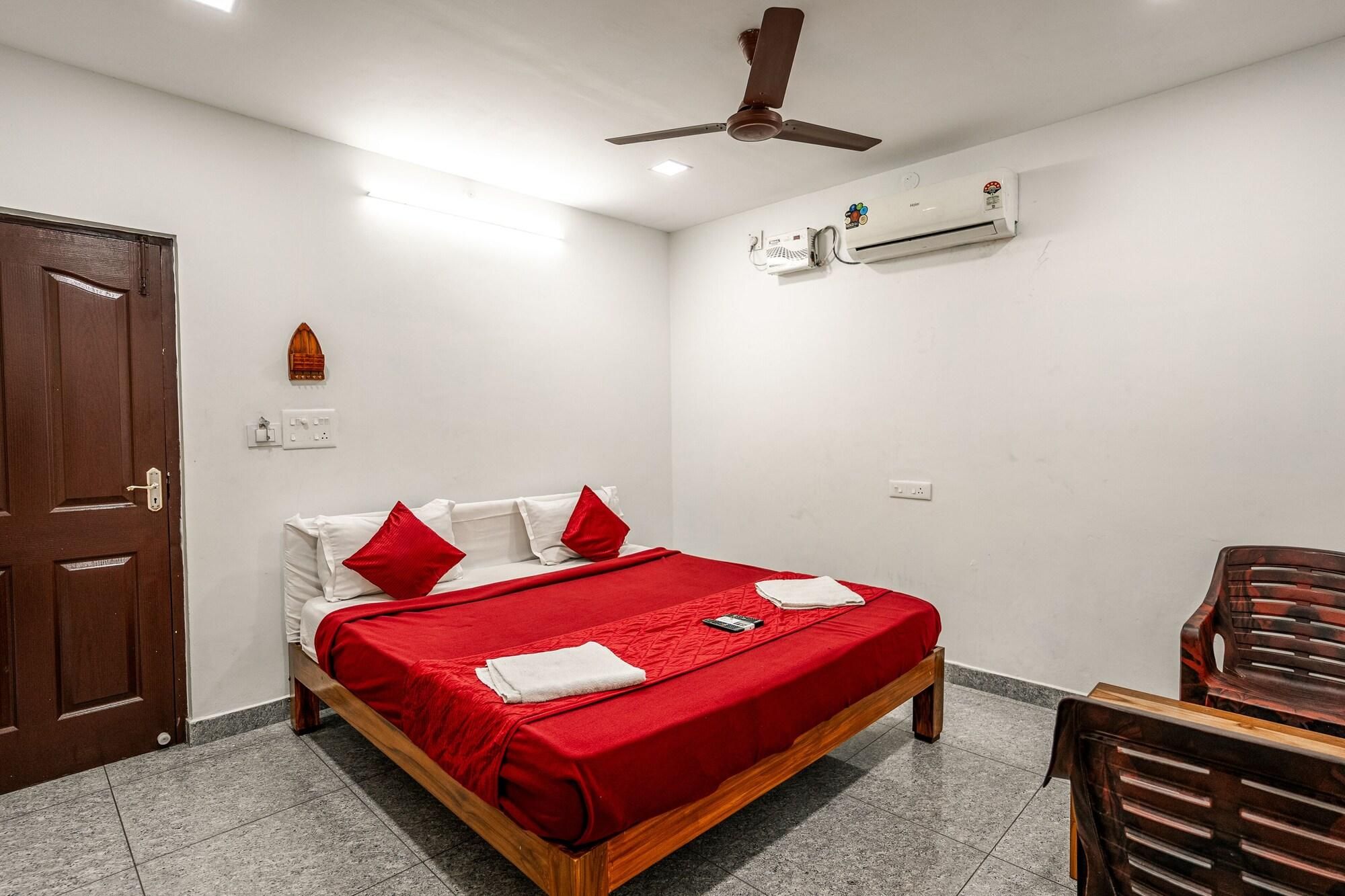 A bedroom with a bed, a ceiling fan, an air conditioning unit, a wooden door, and a chair.