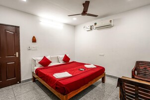 Un dormitorio con cama, ventilador de techo, unidad de aire acondicionado, puerta de madera y una silla.
