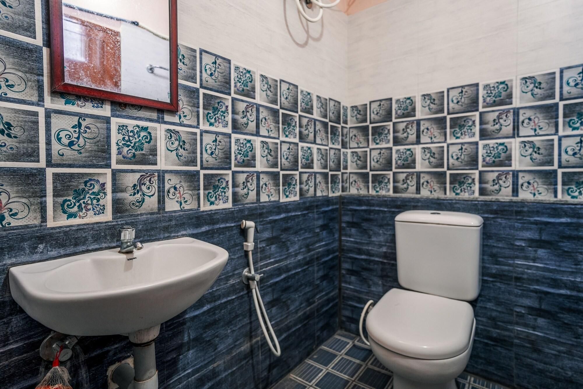 A bathroom with a sink, toilet, and decorative tiles.