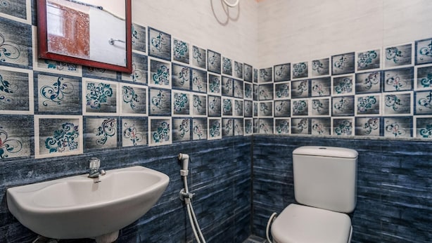Un baño con lavamanos, inodoro y azulejos decorativos.