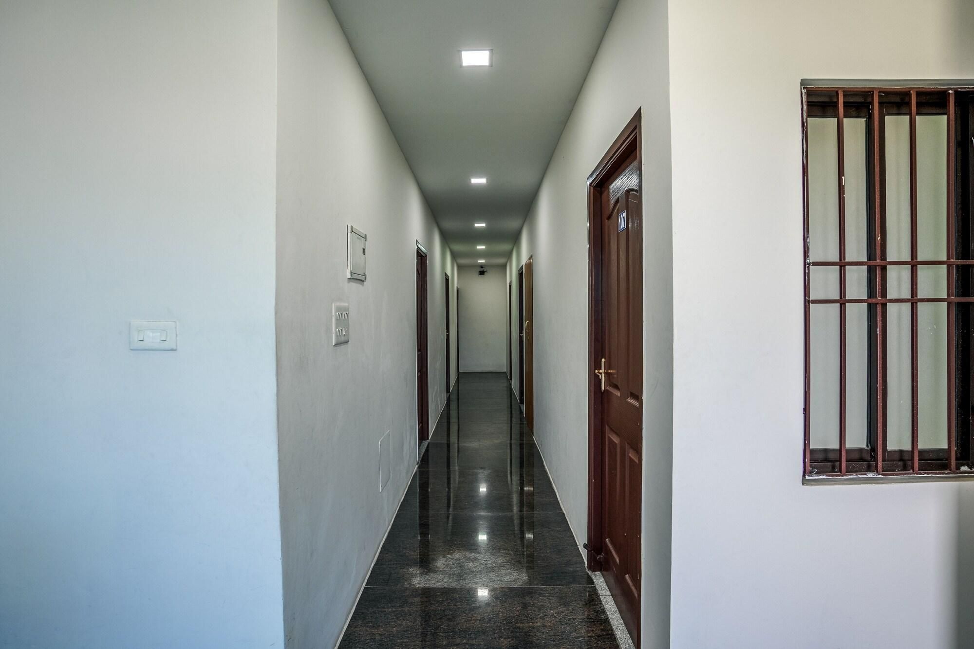 A hallway with doors on both sides, a light switch, and a window with bars.