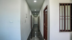 Un pasillo con puertas a ambos lados, un interruptor de luz y una ventana con barrotes.