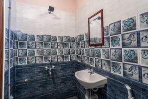 Een badkamer met een wastafel, spiegel en decoratieve tegels.