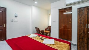 Una habitación de hotel con cama, escritorio y silla. Incluye un armario y un equipo de aire acondicionado.