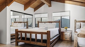 A bedroom with a wooden bed, a nightstand, and a window with a view of a brick building. - Honeypot By Avantstay Indoor Pool Hot Tub (Big Bear Lake)