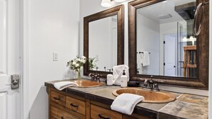 A bathroom with two sinks, a mirror, and a vase of flowers. - Honeypot By Avantstay Indoor Pool Hot Tub (Big Bear Lake)