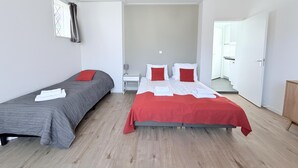 A hotel room with two single beds, a small bedside table with a lamp, and a view of the hallway. - Hotel Cafe De Harmonie (Edam)