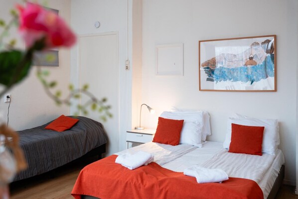 Quarto de hotel com duas camas, uma mesa de cabeceira, um abajur e um quadro na parede.