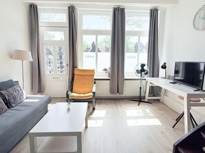 Uma sala de estar moderna com sofá, poltrona, mesa de centro, televisão e radiador.