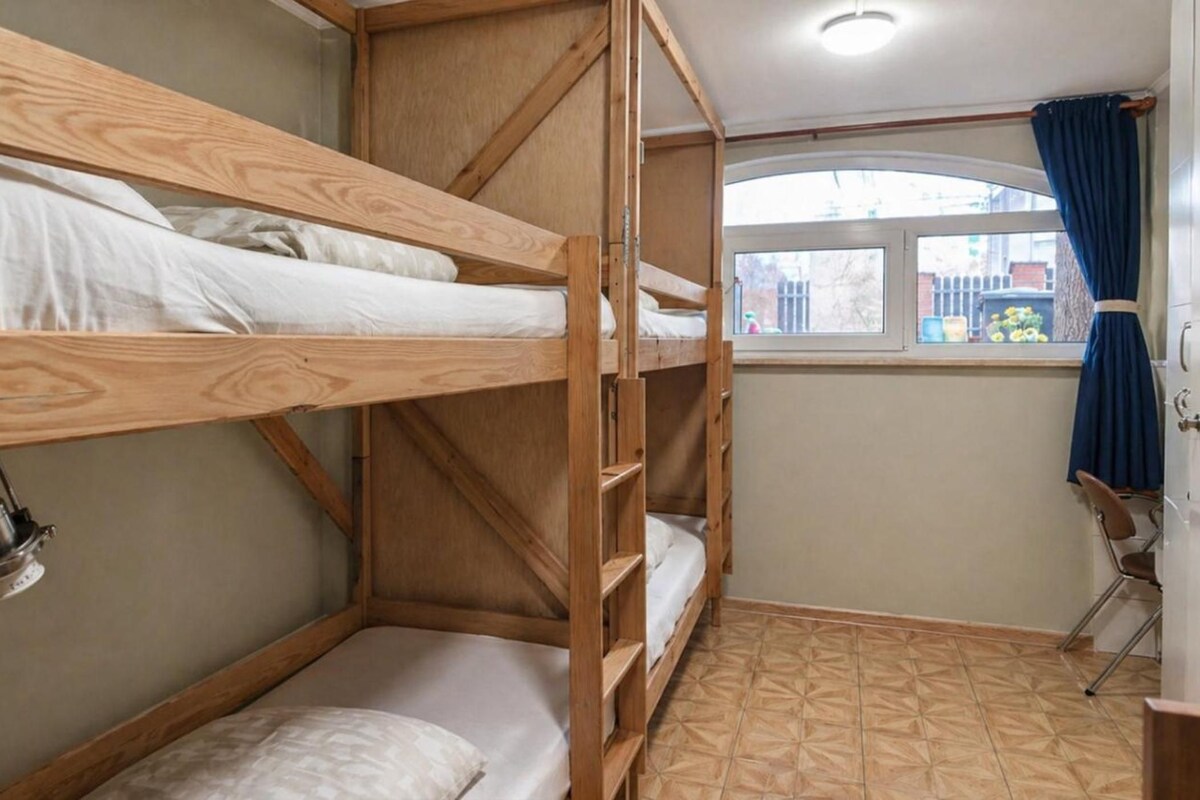 A bunk bed room with a window and a chair.