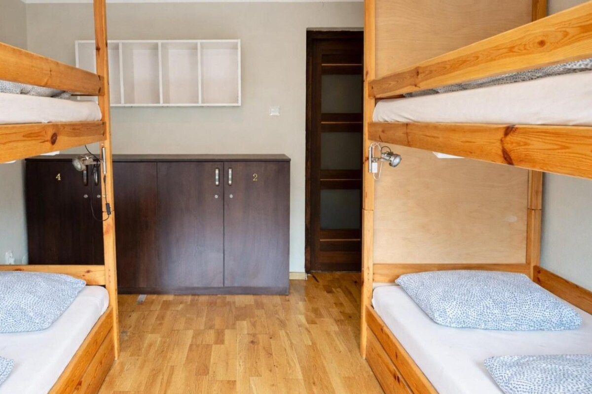 A bunk bed room with wooden frames, a wardrobe, and a cabinet.