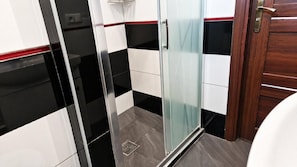 A bathroom with a glass shower enclosure, a white toilet, and a wooden door. - For Rest Hostel (Lublin)