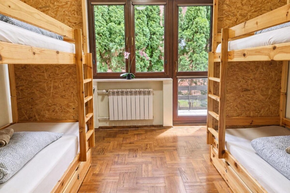 A room with two bunk beds, a radiator, and a window with a view of trees.