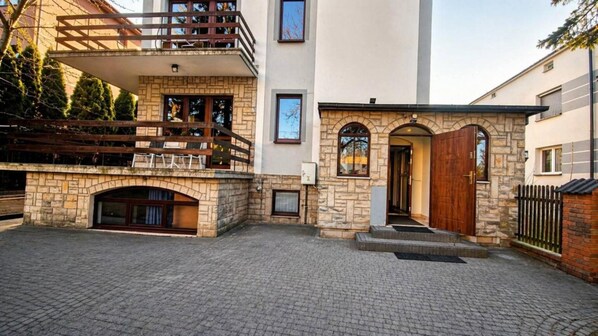A two-story building with a stone facade, a wooden balcony, and a paved courtyard. - For Rest Hostel (Lublin)