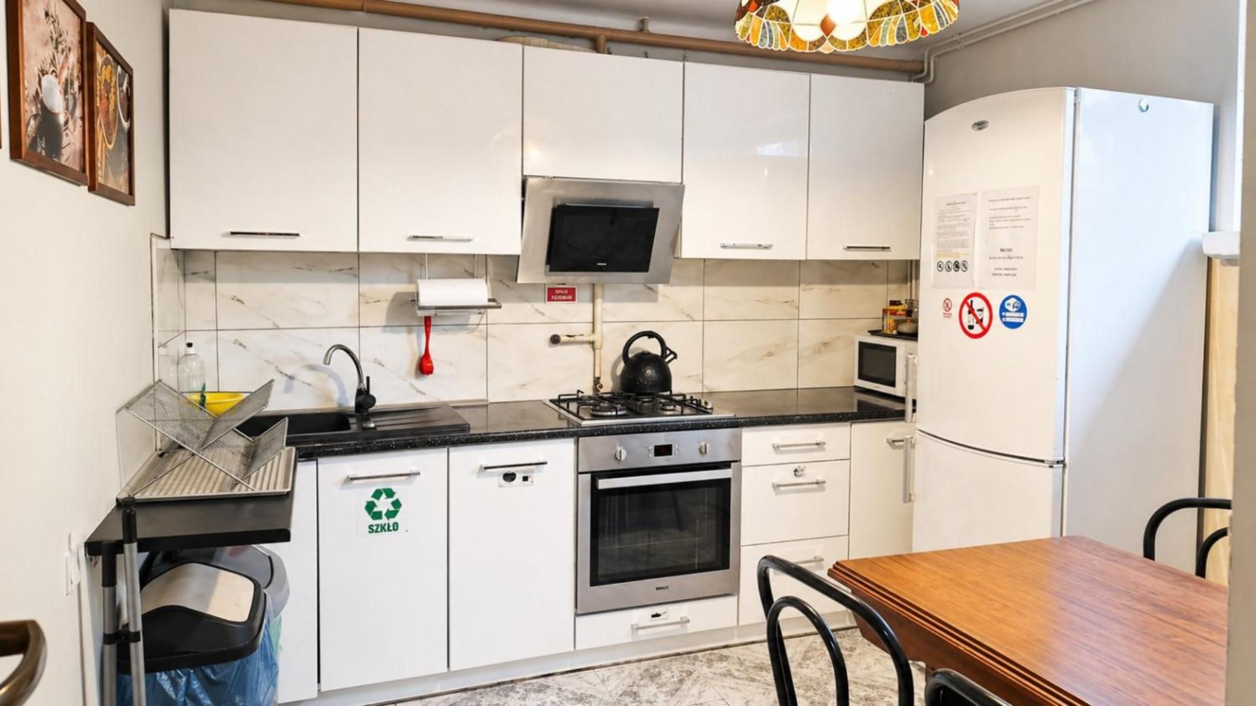 A modern kitchen with white cabinets, a stainless steel stove, a microwave, and a refrigerator.