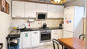 A modern kitchen with white cabinets, a stainless steel stove, a microwave, and a refrigerator. - For Rest Hostel (Lublin)