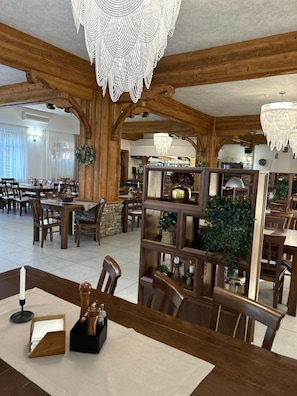 Un amplio comedor con vigas de madera, varias mesas y sillas.