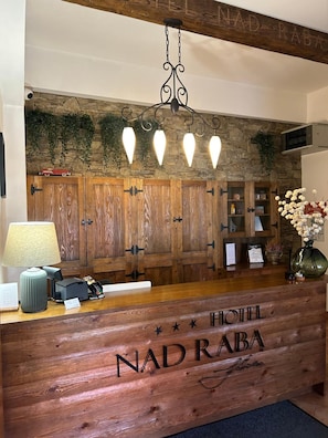 Una mesa de recepción con frente de madera y el nombre 'NAD RABA HOTEL' bien visible.