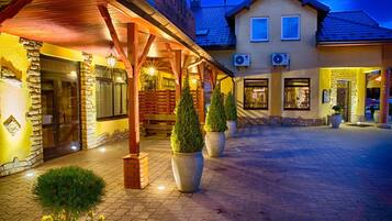 Ein Hotel mit überdachter Außenfläche, Steinwänden und Topfpflanzen.