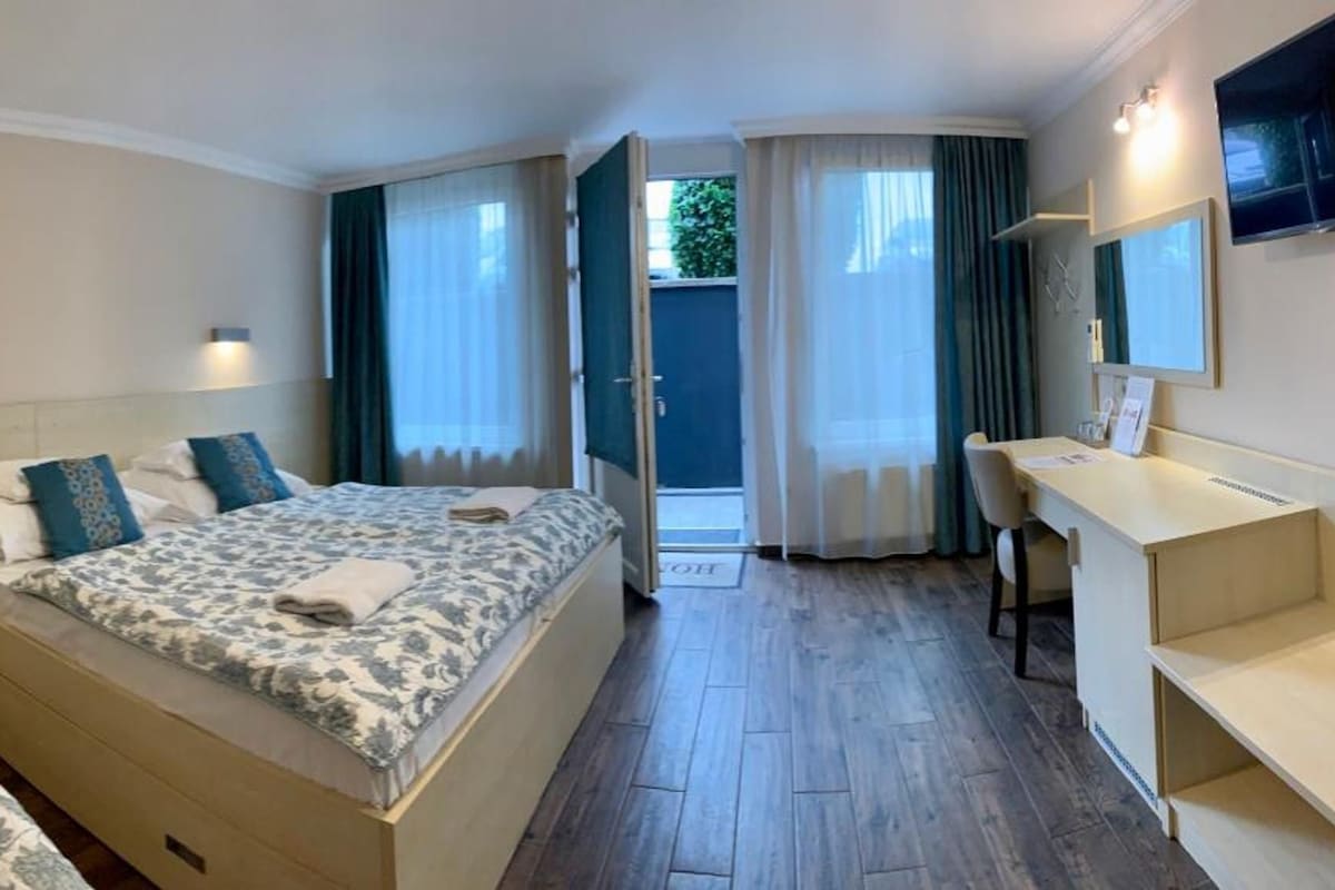 Habitación de hotel con dos camas, un escritorio, un espejo y vistas al exterior.