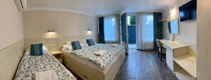 Quarto de hotel com duas camas, uma mesa, um espelho e vista para o exterior.