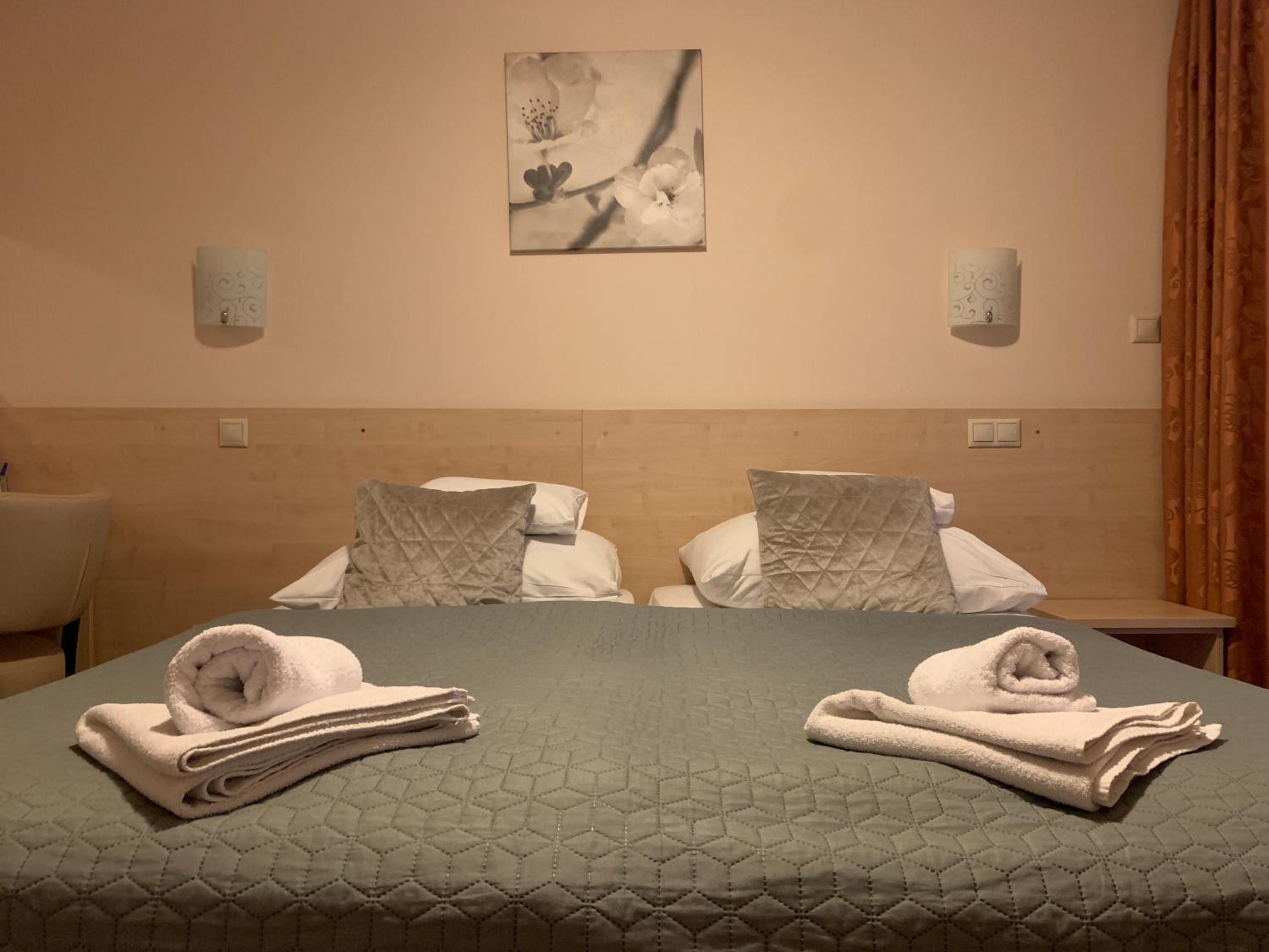 Una habitación de hotel con cama, dos almohadas, una obra de arte colgada en la pared y una mesita de noche.