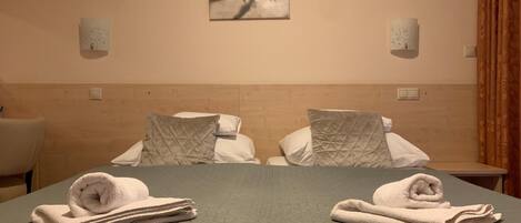 Una habitación de hotel con cama, dos almohadas, una obra de arte colgada en la pared y una mesita de noche.