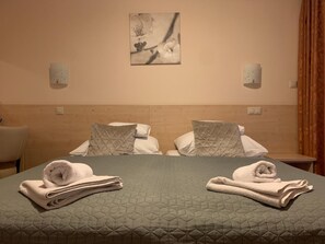Una habitación de hotel con cama, dos almohadas, una obra de arte colgada en la pared y una mesita de noche.