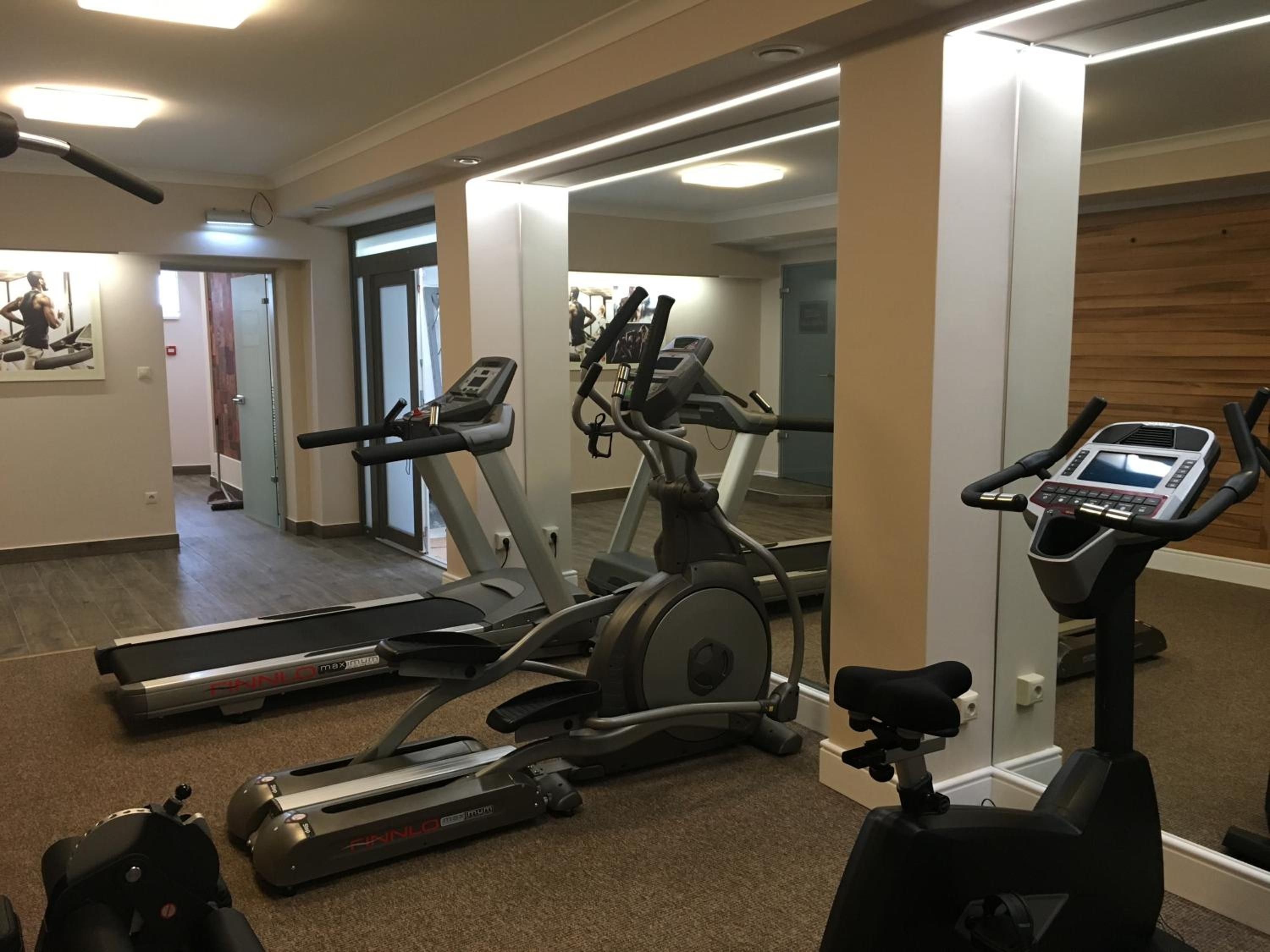 Ein Fitnessraum mit Laufbändern, einem Crosstrainer und einem Ergometer.