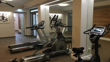 Un gimnasio con cintas de correr, una elíptica y una bicicleta estática.