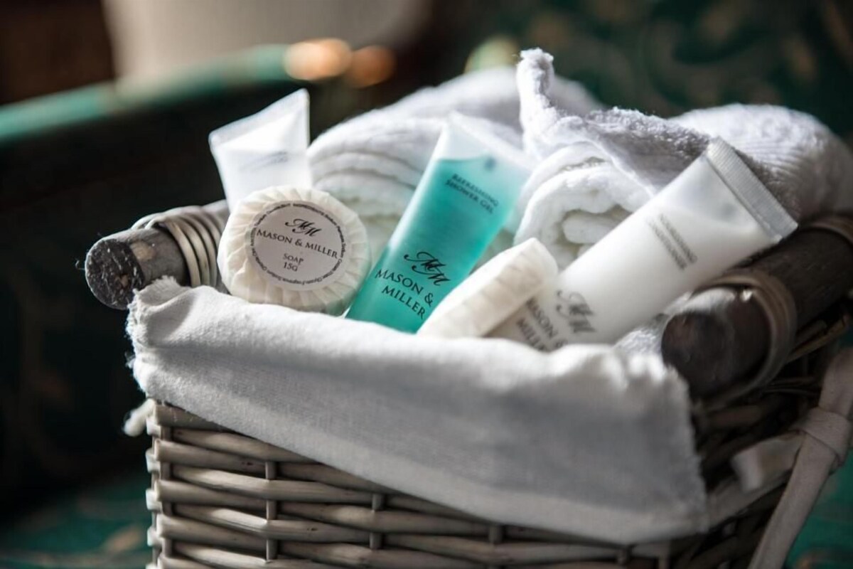 A wicker basket containing various toiletries including a bar of soap, a shower gel bottle, and a tube of cream.