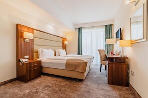 A hotel room with a large bed, bedside tables, a desk, and a chair. - Radsor Hotel (Rasnov)
