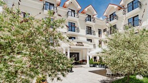 Un hotel con entrada principal, varios balcones y zonas verdes circundantes.