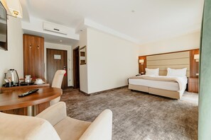Habitación de hotel con cama, escritorio con control remoto, silla y minibar.