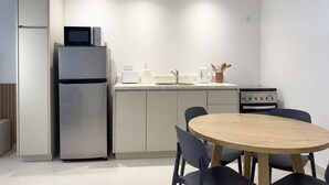 A compact kitchen with a refrigerator, microwave, toaster, and stove. There is a round wooden table with chairs. - A more spacious family apartment with a full kitchen. (Azul)