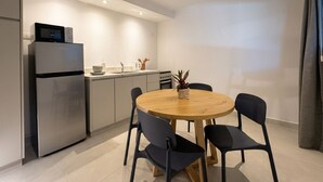 A modern kitchen with a round dining table, chairs, a refrigerator, and a microwave. - A more spacious family apartment with a full kitchen. (Azul)