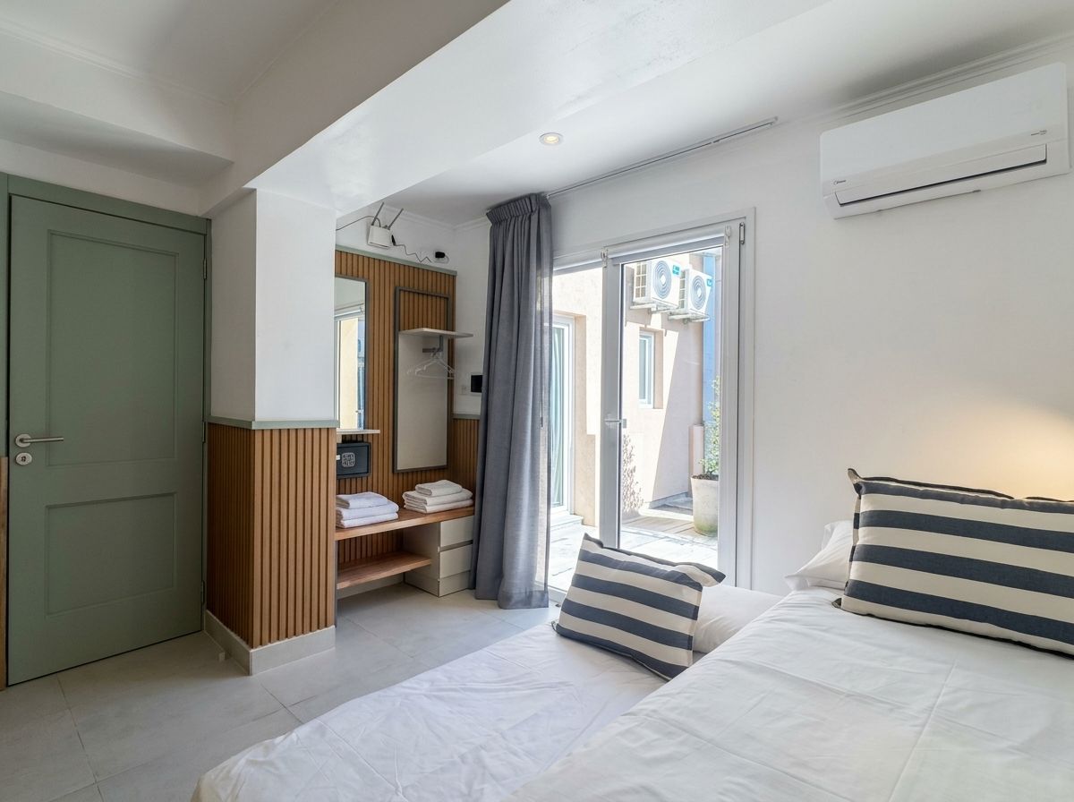 Hotellihuone, jossa on sänky, vaatekaappi, peilillä varustettu meikkipöytä ja uloskäyntiä varten liukuovet.