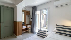 A hotel room with a bed, a wardrobe, a vanity with a mirror, and a sliding glass door to the outside. - A more spacious family apartment with a full kitchen. (Azul)