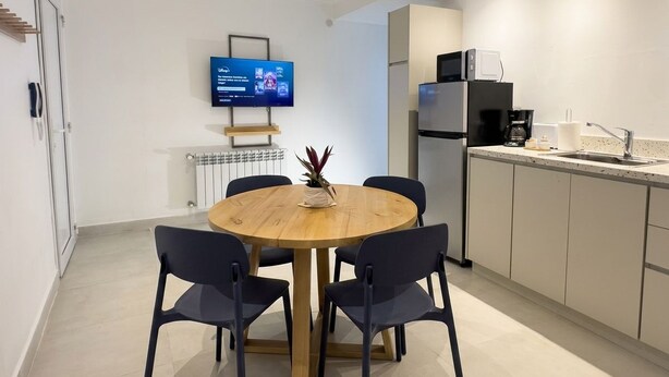 A modern kitchen with a dining area, a flat-screen TV mounted on the wall, and a refrigerator. - A more spacious family apartment with a full kitchen. (Azul)