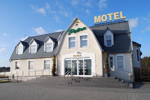 Un edificio de dos pisos con un letrero que dice 'Motel', un letrero 'Petro' y un letrero 'Węcze'.